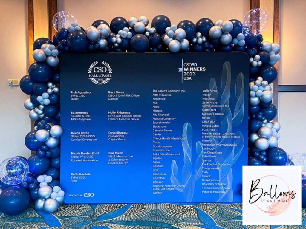 Decorative balloon arrangement for a corporate event, featuring a blue-themed display with company logos and honorees