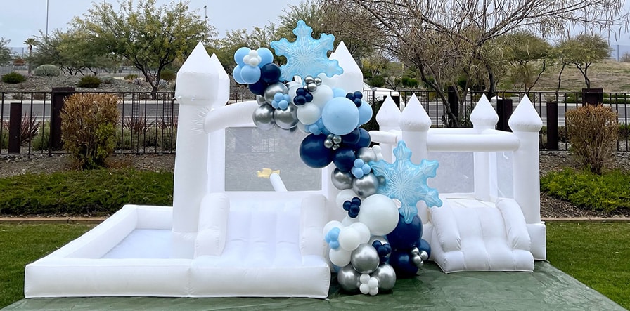 Winter-themed balloon decor on a white bounce house in Mesa